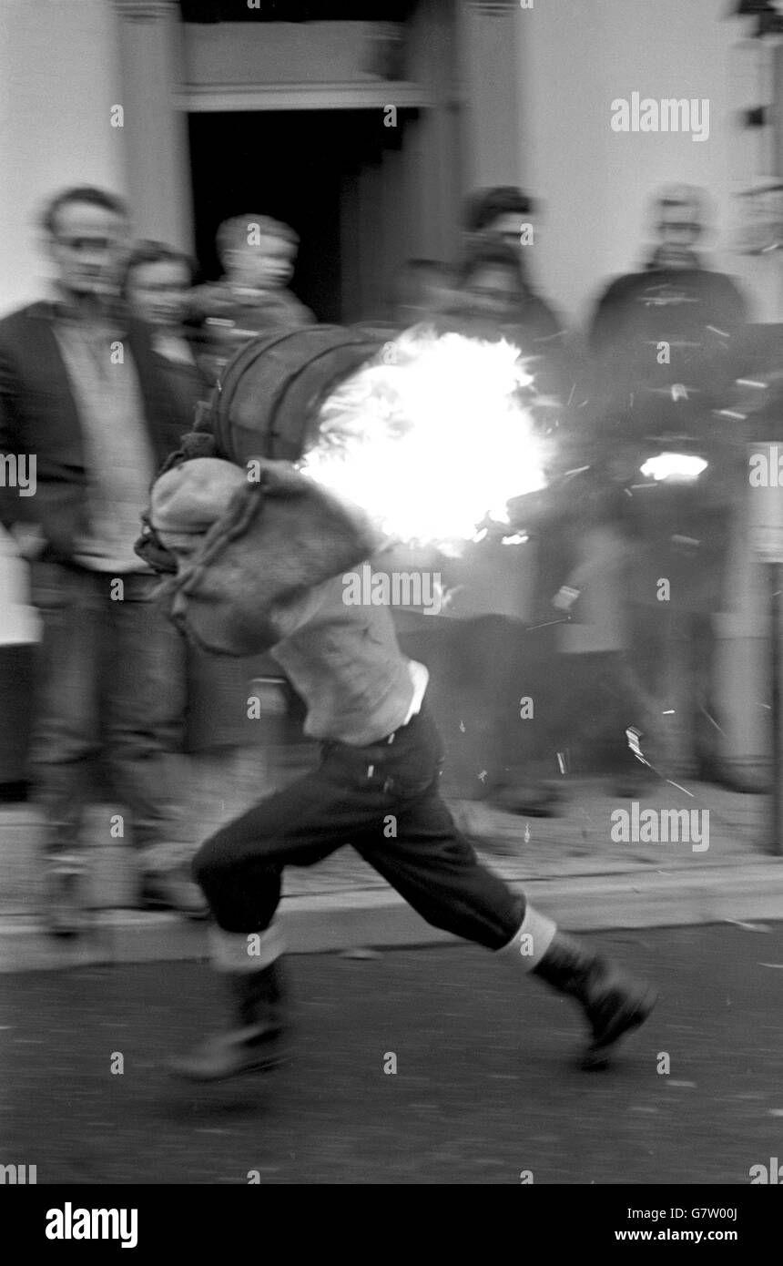 Tar Barrel Burning Ceremony - Ottery St Mary's. Ein Junge rennt mit einem brennenden Fass während der Veranstaltung der Schüler durch die Straße. Stockfoto