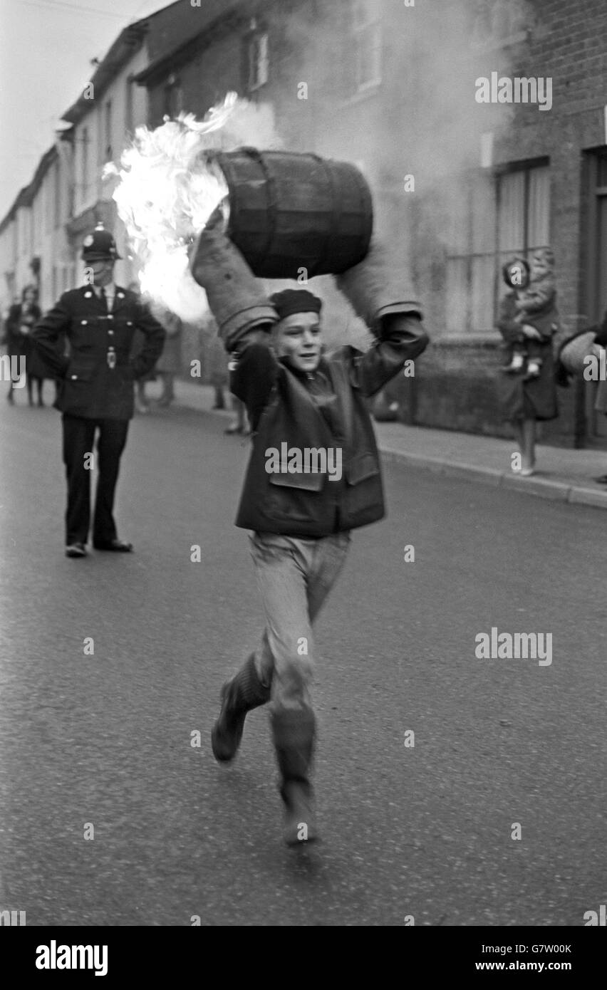 Tar Barrel Burning Ceremony - Ottery St Mary's. Ein Junge rennt während der Veranstaltung der Schüler mit einem brennenden Fass durch die Straße. Stockfoto