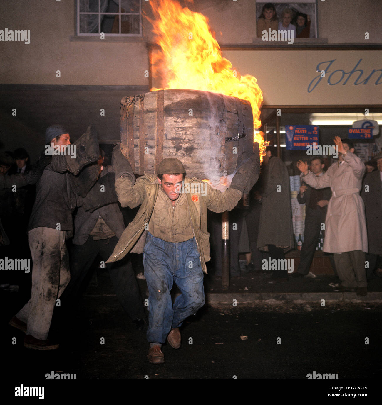 Tar Barrel Burning Ceremony - Ottery St Mary's. Ein Mann trägt ein brennendes Fass auf seinen Schultern, während die Menschen darauf schauen. Stockfoto