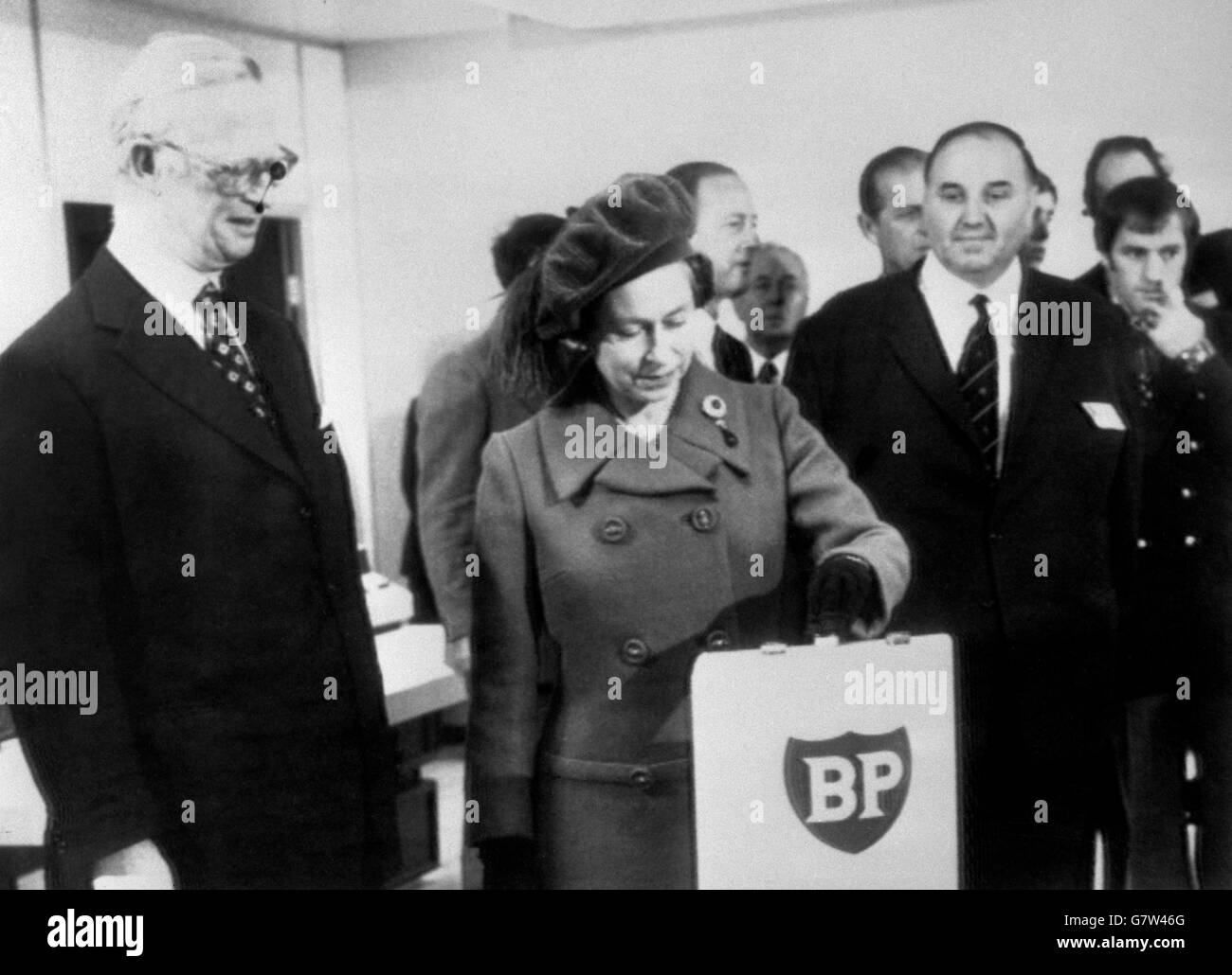 Die Queen, flankiert von Sir Eric Drake und Colin Smith, drückt einen Knopf im Kontrollraum von Dyce, nahe Aberdeen, um den Ölfluss vom Forties Field in der Nordsee zur 237 Meilen entfernten BP-Raffinerie Grangemouth zu starten. Stockfoto