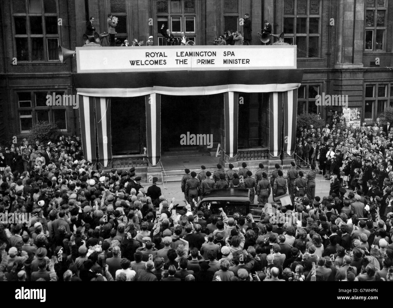 Mit Lady Eden in der Nähe winkt der Premierminister Sir Anthony Eden den jubelnden Massen zu, die die Straße unten vom Balkon des Rathauses in Leamington Spa aus bedrängen. Sir Anthony, der Leamington und Warwick seit 1923 im Parlament vertreten hat, besuchte den Wahlkreis zum ersten Mal seit seiner Ernennung zum Premierminister und Hunderte von Menschen versammelten sich, um seiner Ernennung Tribut zu zollen. Stockfoto