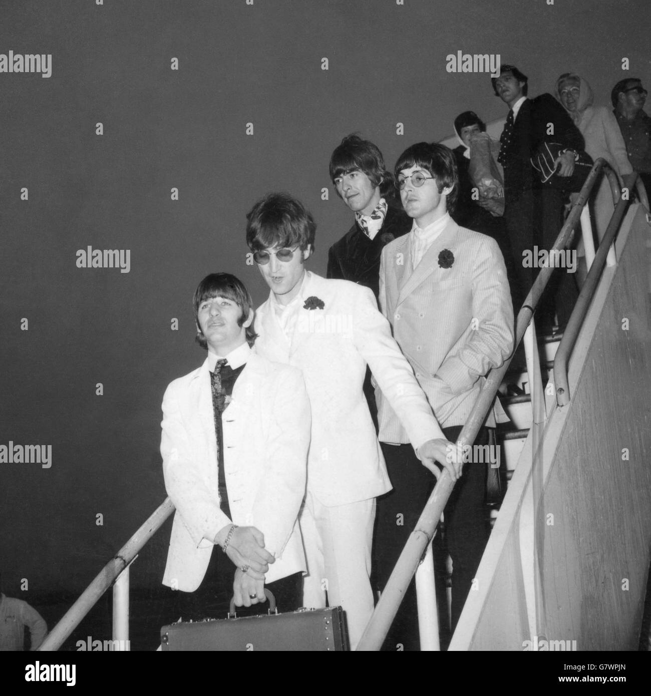 Die Beatles stellten sich vor, als sie heute (Mittwoch) von ihrer amerikanischen Tour am Flughafen London aus ihrem Flugzeug kamen. (Von links nach rechts) Ringo Starr in weißer Jacke und schwarzer Hose, JOHN LENNON in weißem Anzug und Sonnenbrille, GEORGE HARRISON in einem schwarzen Samtanzug und PAUL McCartney, der einzige Beatles-Junggeselle, der bestritt, dass er heiraten wollte. Trotz der frühen Stunde waren etwa 250 schreiende Mädchen-Fans auf dem Balkon des Queen's Building, um die Beatles von ihrer Drama-Tour zu begrüßen. Stockfoto