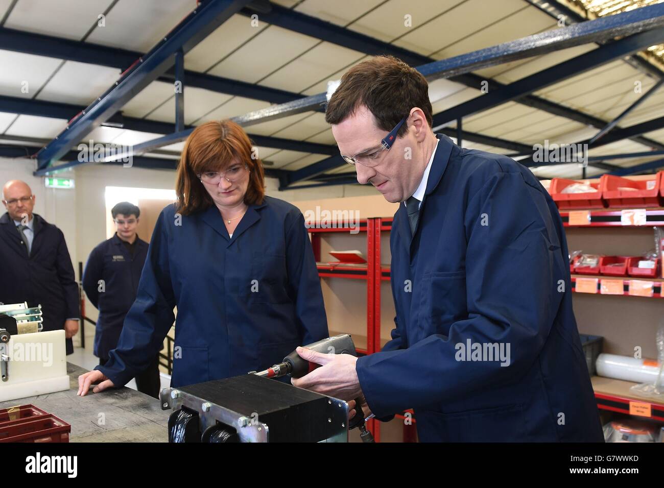 Kanzler George Osborne zieht mit einer Luftbohrmaschine eine Mutter an, während der Minister für Bildung Nicky Morgan (links) bei einem Besuch des EPS-Ingenieurunternehmens in Loughborough, Leicestershire, war. Stockfoto
