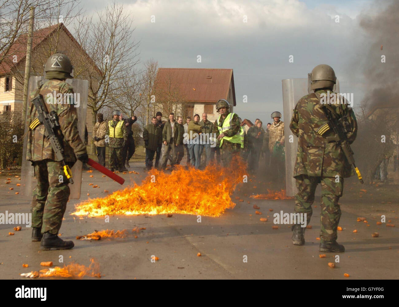 Soldaten sehen sich nach einem Scheinaufstände einem wütenden Haufen Aufständischer gegenüber. Stockfoto