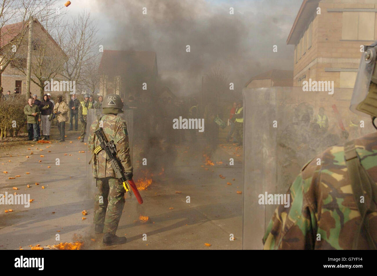 Soldaten sehen sich nach einem Scheinaufstände einem wütenden Haufen Aufständischer gegenüber. Stockfoto