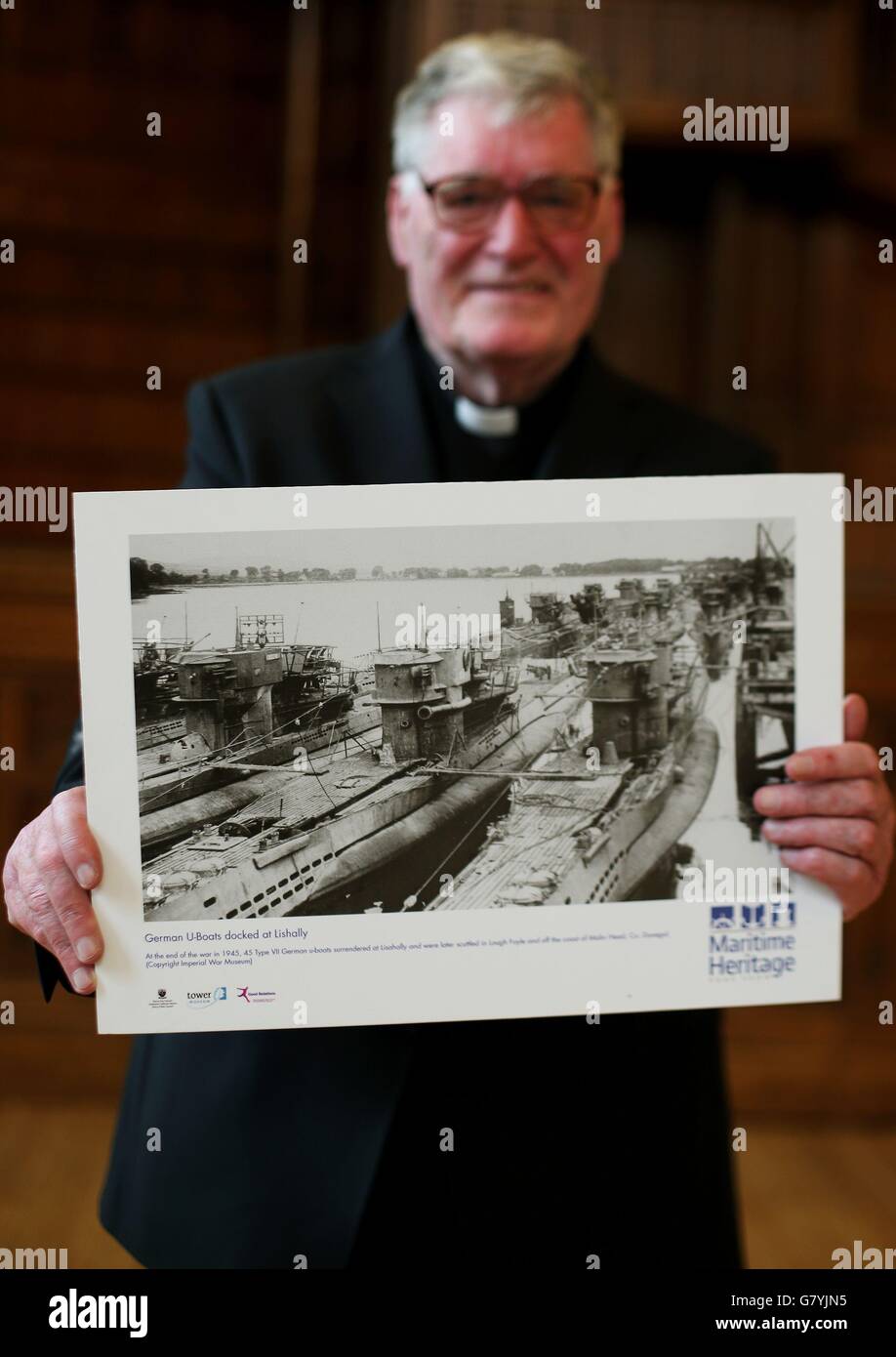 FR Arthur O'Reilly, in der Guildhall, Londonderry, hält ein Foto von deutschen U-Booten, die nach dem Ende des Zweiten Weltkriegs vor 70 Jahren an diesem Wochenende in Lishly auf dem Fluss Foyle in Londonderry, Nordirland, angedockt sind. Stockfoto