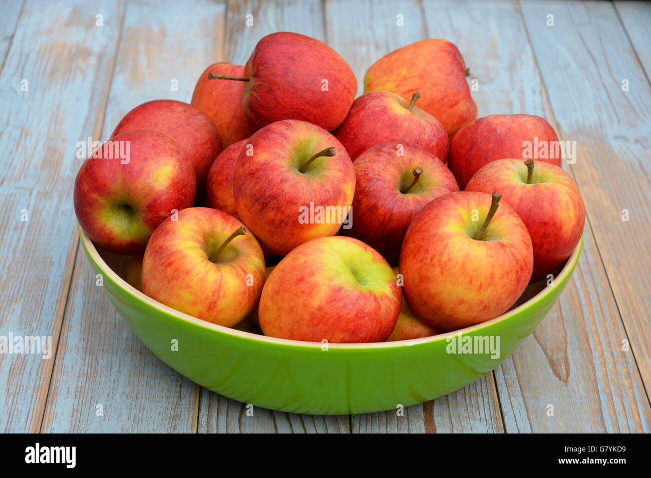 Frische rote, gelbe und grüne Äpfel in einer grünen Schale auf hölzernen Hintergrund Stockfoto