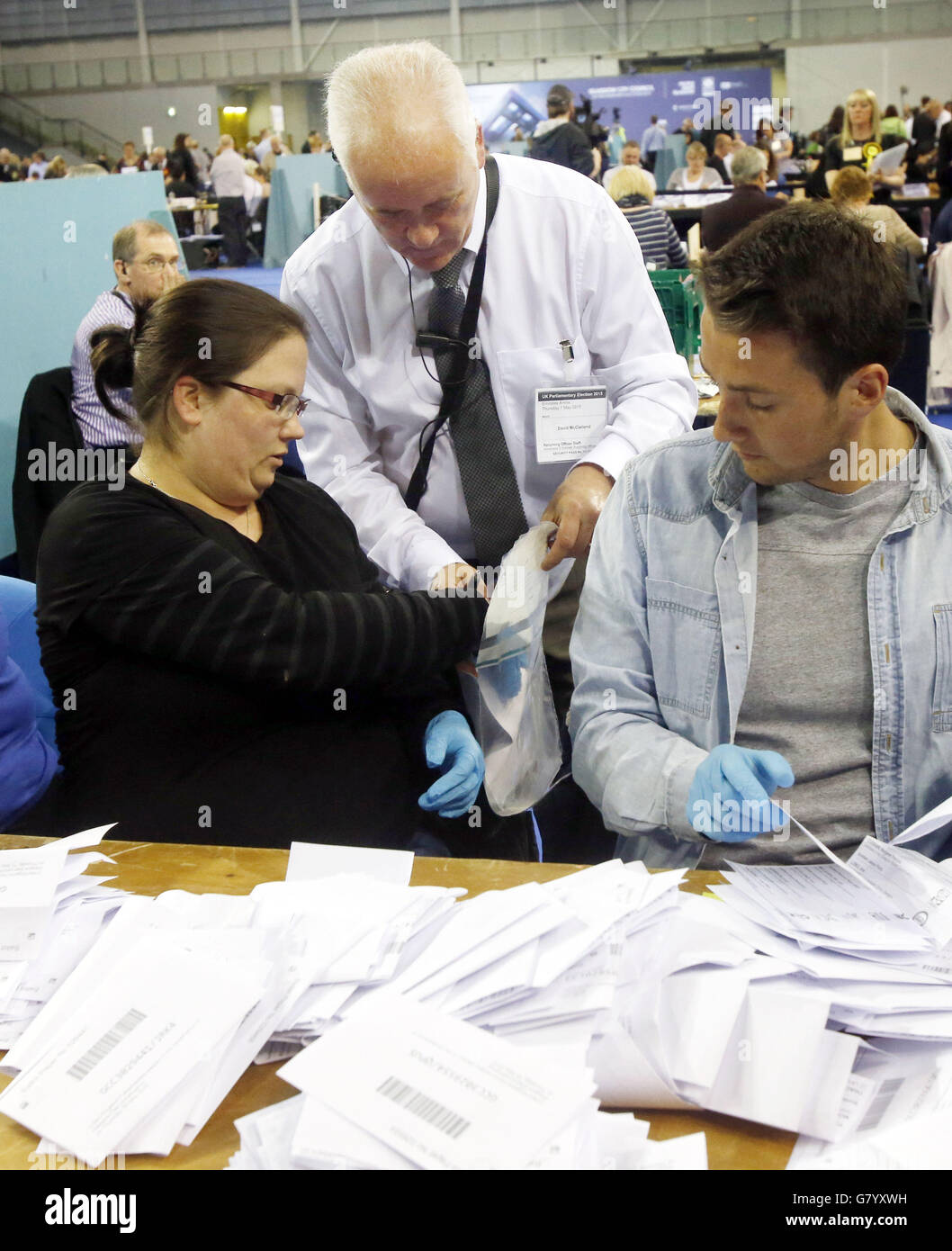 Die Mitarbeiter der Zählung tragen blaue Handschuhe, wenn sie bei der allgemeinen Wahlzählung für Wahlkreise in Glasgow in der Emirates Arena in Glasgow nach einer möglichen betrügerischen Abstimmung suchen. Stockfoto