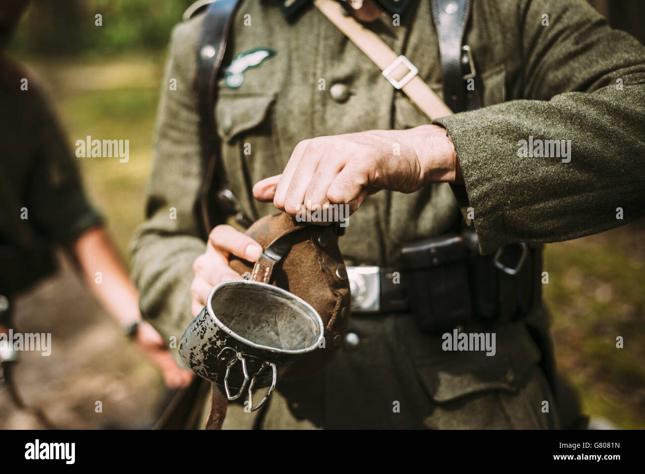 Nicht identifizierte Re-Enactor verkleidet als Soldat im zweiten Weltkrieg öffnet Flasche mit Wasser. Stockfoto