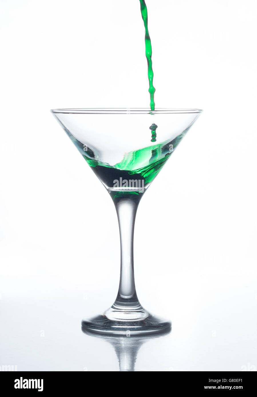 Gießen rotes und grünes alkoholisches Getränk in einem Cocktailglas isoliert auf weißem Hintergrund Stockfoto