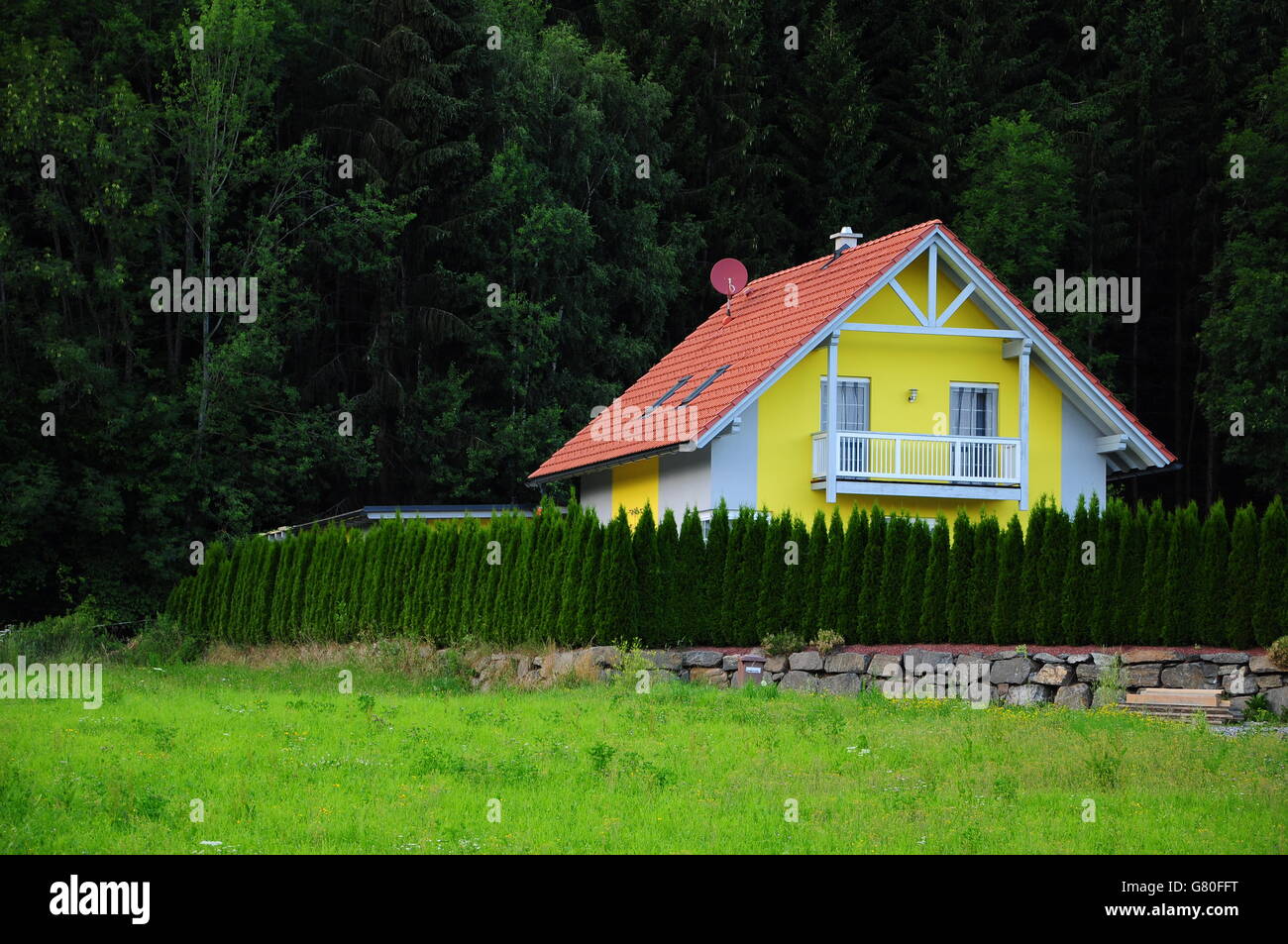 Schöne und bunte Häuschen umgeben von Zypressen Zaun und Wald im Hintergrund Stockfoto Schöne und bunte Häuschen umgeben von Zypressen Zaun und Wald im Hintergrund Stockfoto