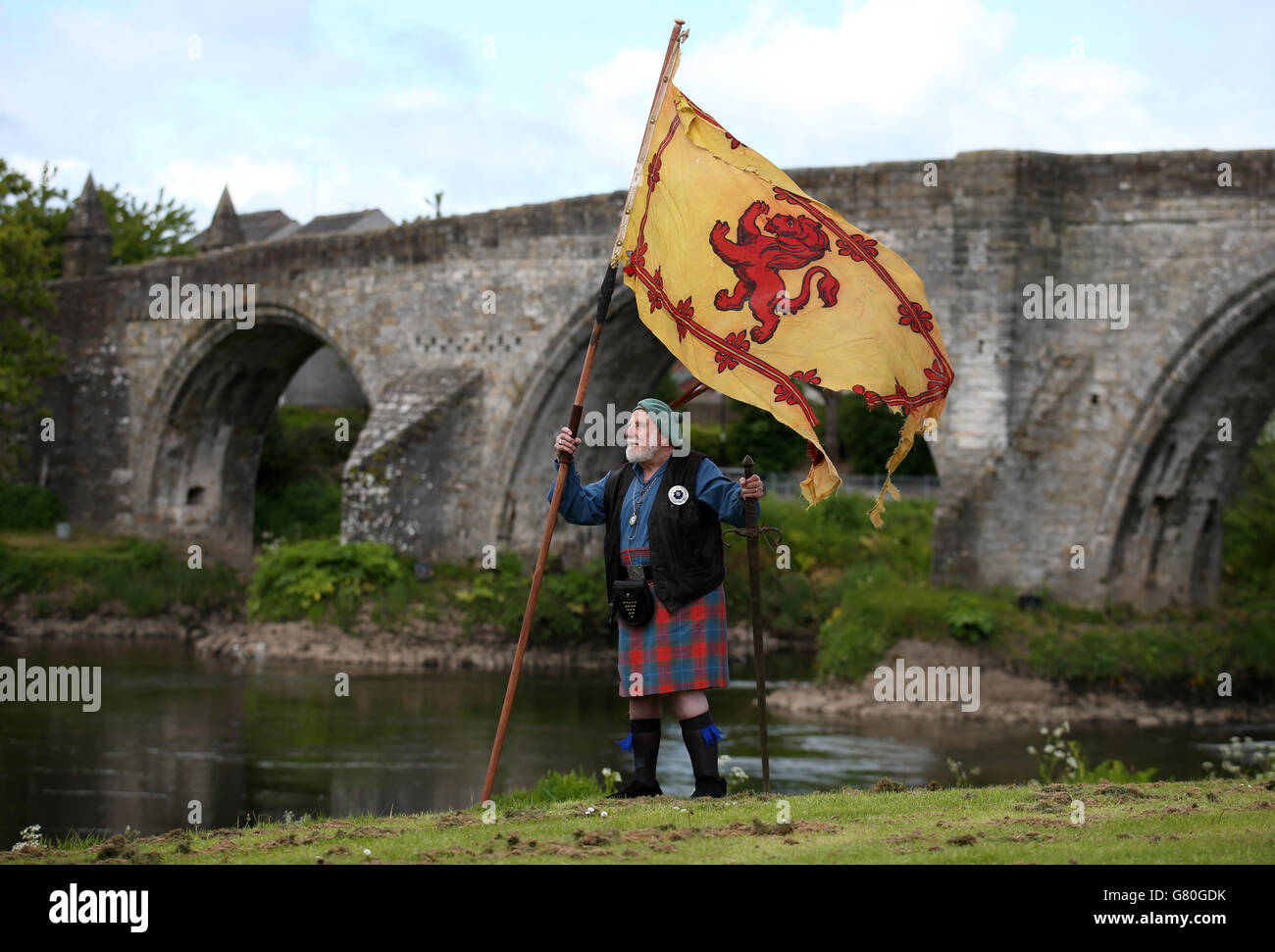 Das Mitglied der Wallace Society Eddie McNeill aus Strachur schwingt eine wehende Löwenfahne von der Stirling Bridge als Denkmal an der Stelle der "Braveheart Schlacht", wo William Wallace und Andrew de Moray Schottland zum Sieg bei der Schlacht von Stirling Bridge im Jahr 1297 führten. Stockfoto