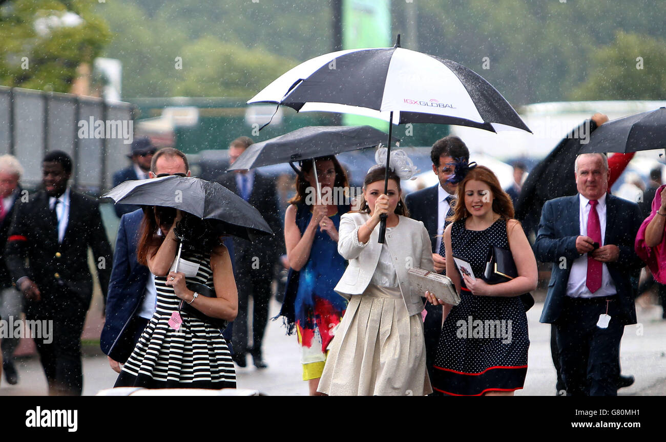 Pferderennen - 2015 Investec Derby Festival - Ladies Day - Epsom Racecourse. Am Ladies Day des Investec Derby Festivals 2015 auf der Epsom Racecourse, Epsom, nutzen Damen einen Regenschirm, um sich vor dem Regen zu schützen. Stockfoto