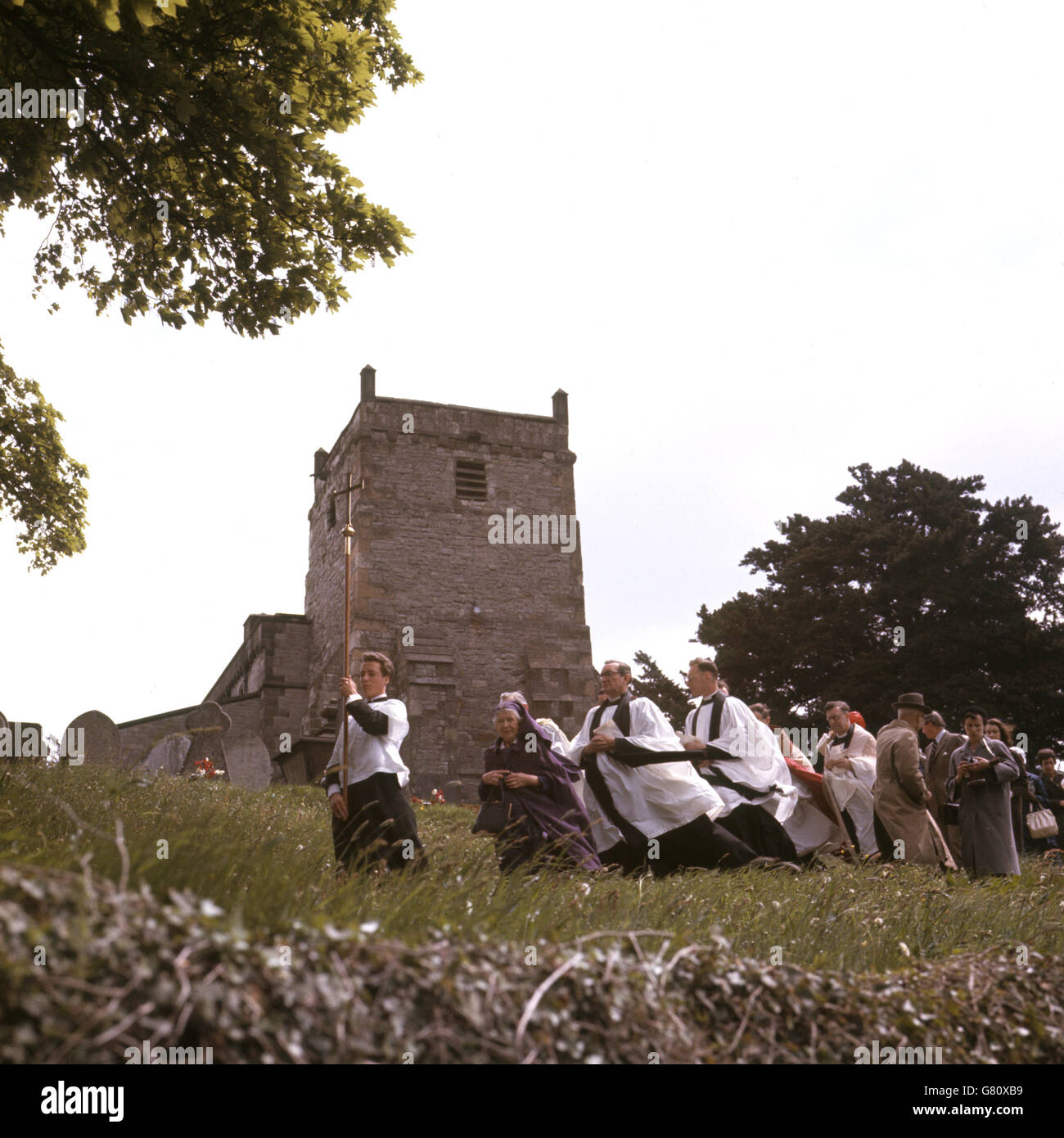 Bräuche und Traditionen - Brunnenverkleiden - Tissington, Derbyshire. Der Klerus in Prozession aus der Kirche, um die Brunnen in Tissington, Derbyshire zu segnen. Stockfoto