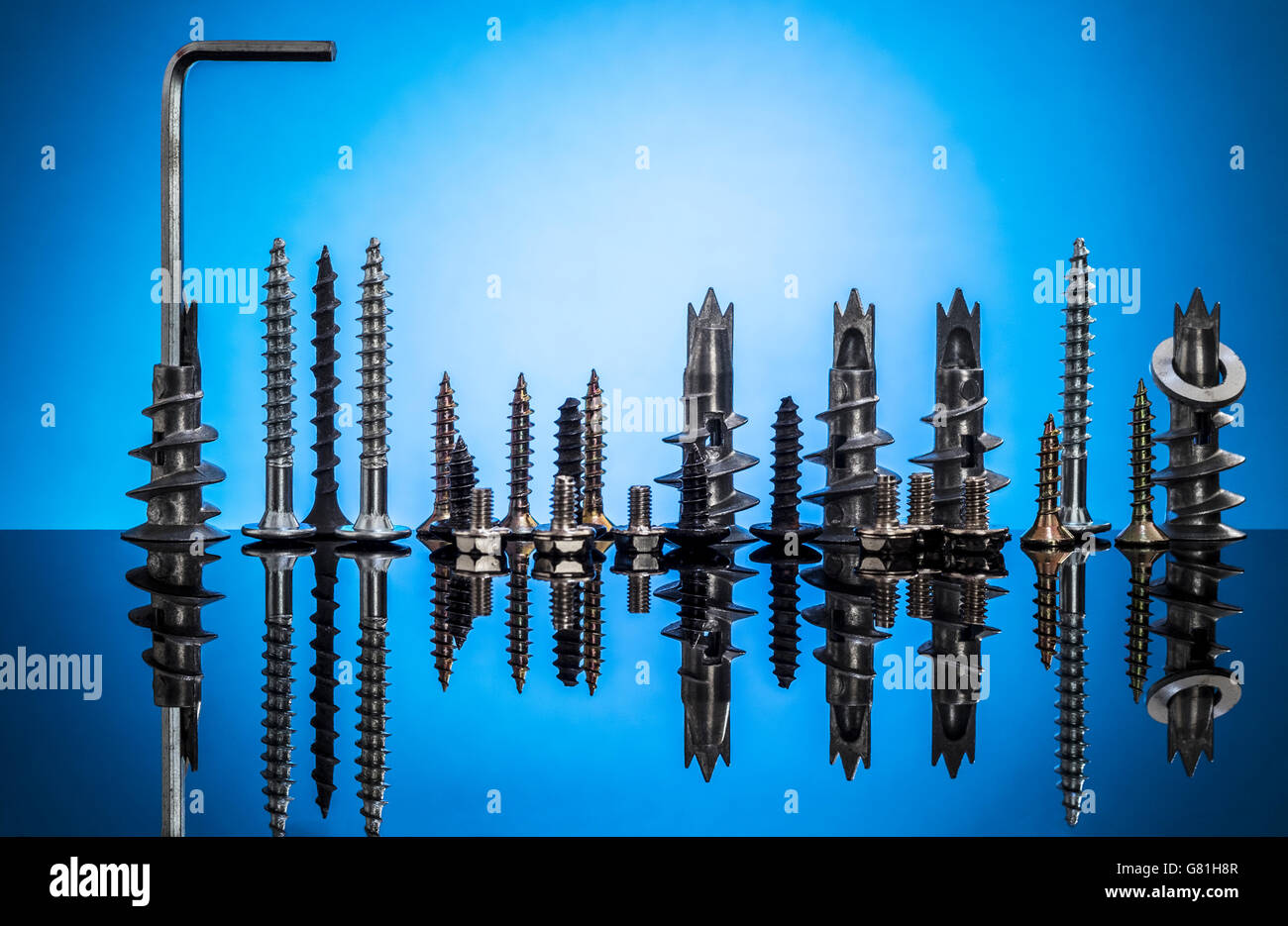 Sammlung von Schrauben und Bolzen auf blauem Grund repräsentieren die Skyline einer Stadt und ihre Reflexion Stockfoto