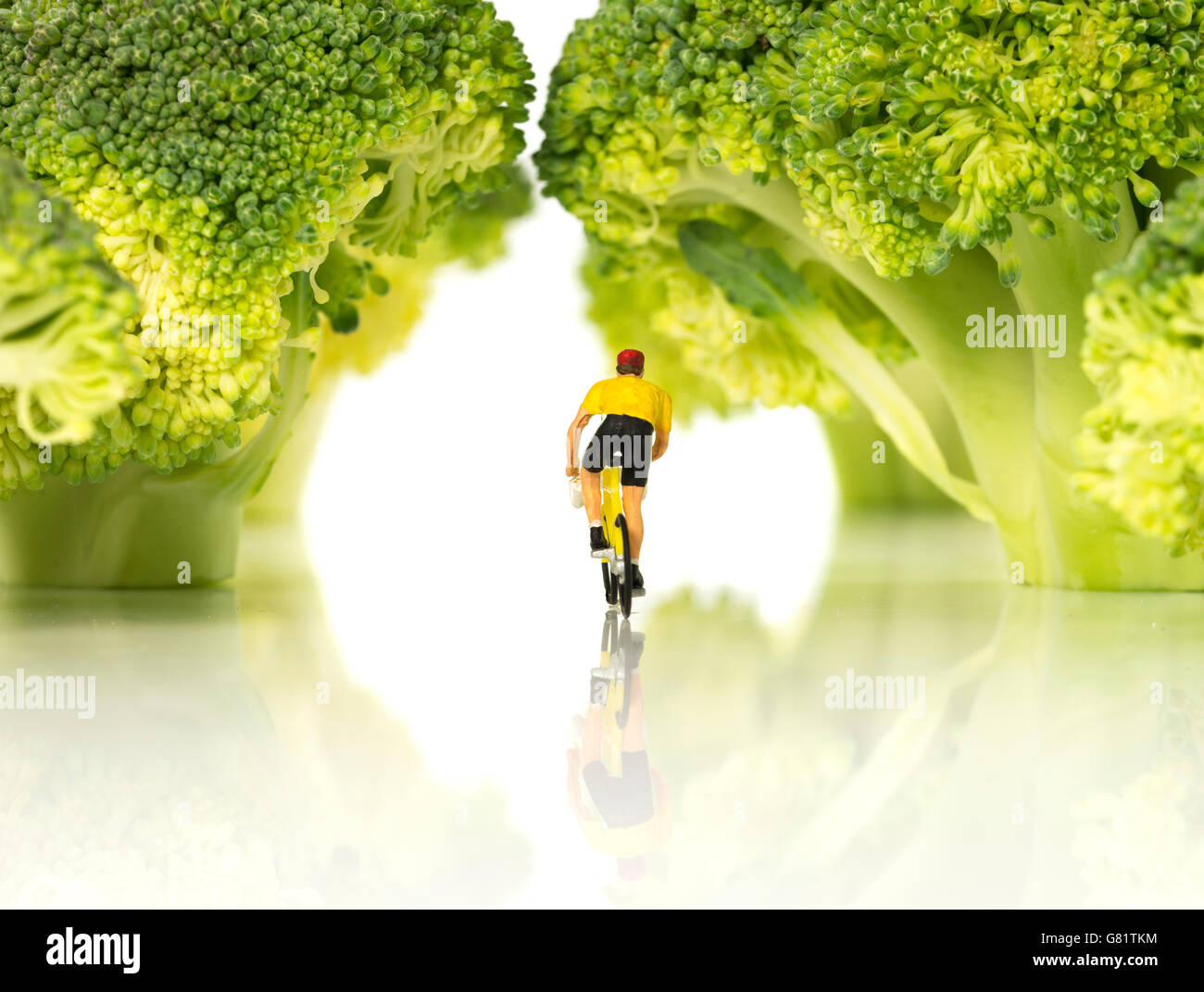 Miniatur Figur Mann mit Fahrrad im gelben Trikot auf tour de France im grünen Wald Stockfoto