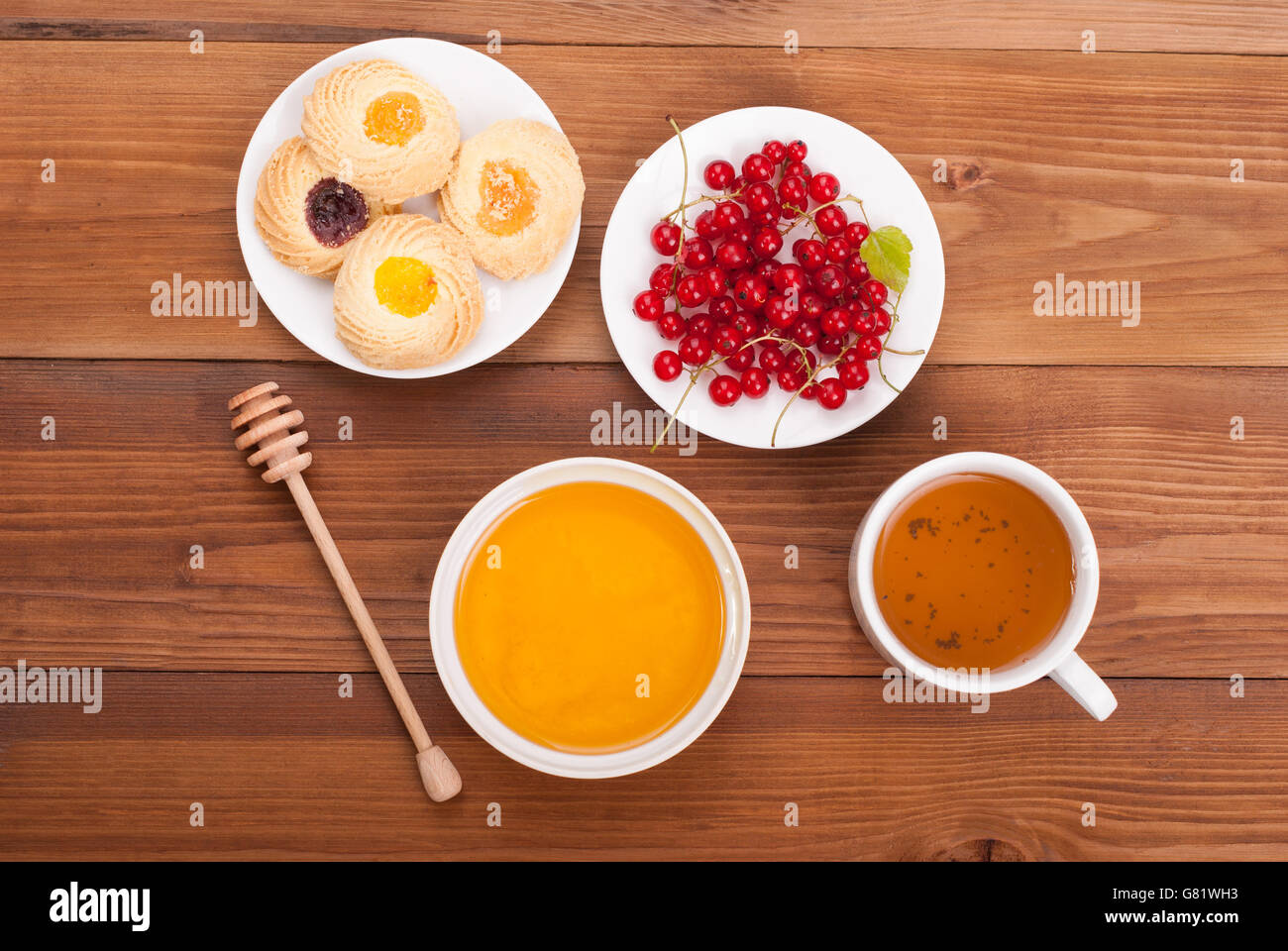 Tasse Tee Honig Kekse und Johannisbeeren auf einem Holztisch. Ansicht von oben. Stockfoto