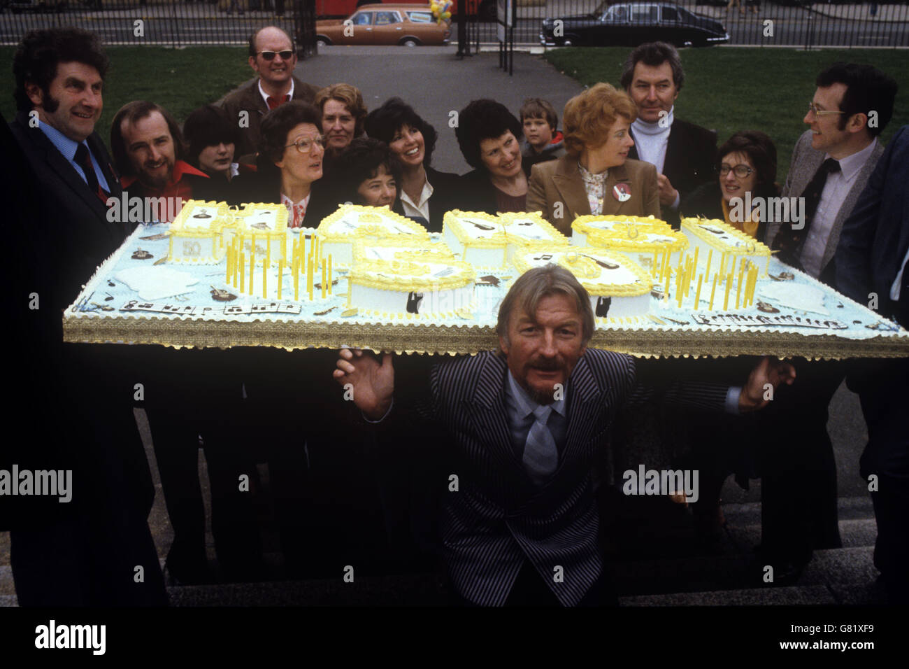 Der deutsche Bandleader James Last (im Vordergrund) mit der 200 Pfund schweren Torte, die ihm von Fans zu seinem 50. Geburtstag überreicht wurde. Stockfoto