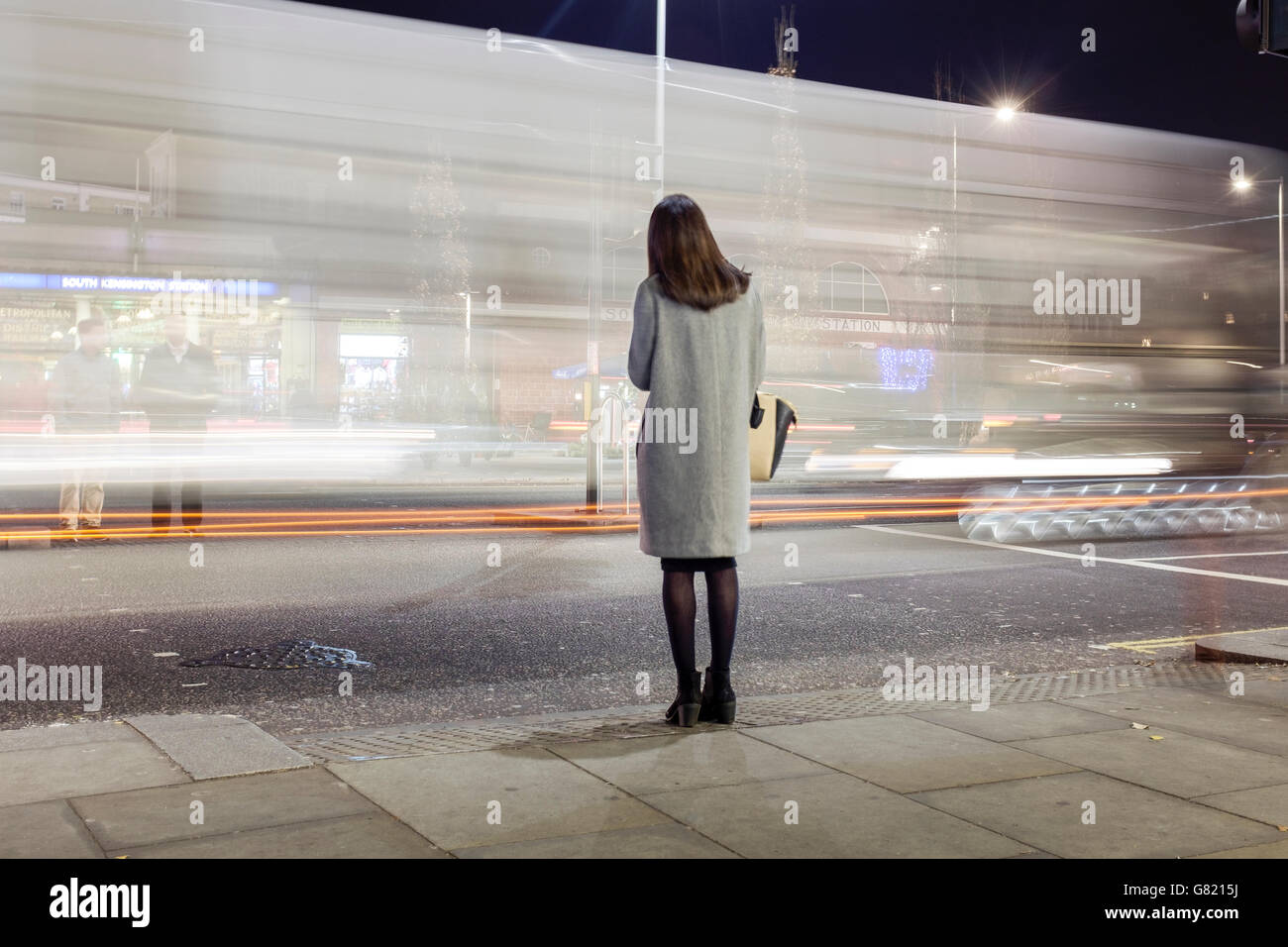 UK, London, South Kensington-Frau wartet, stark befahrene Straße in der Nacht zu überqueren Stockfoto