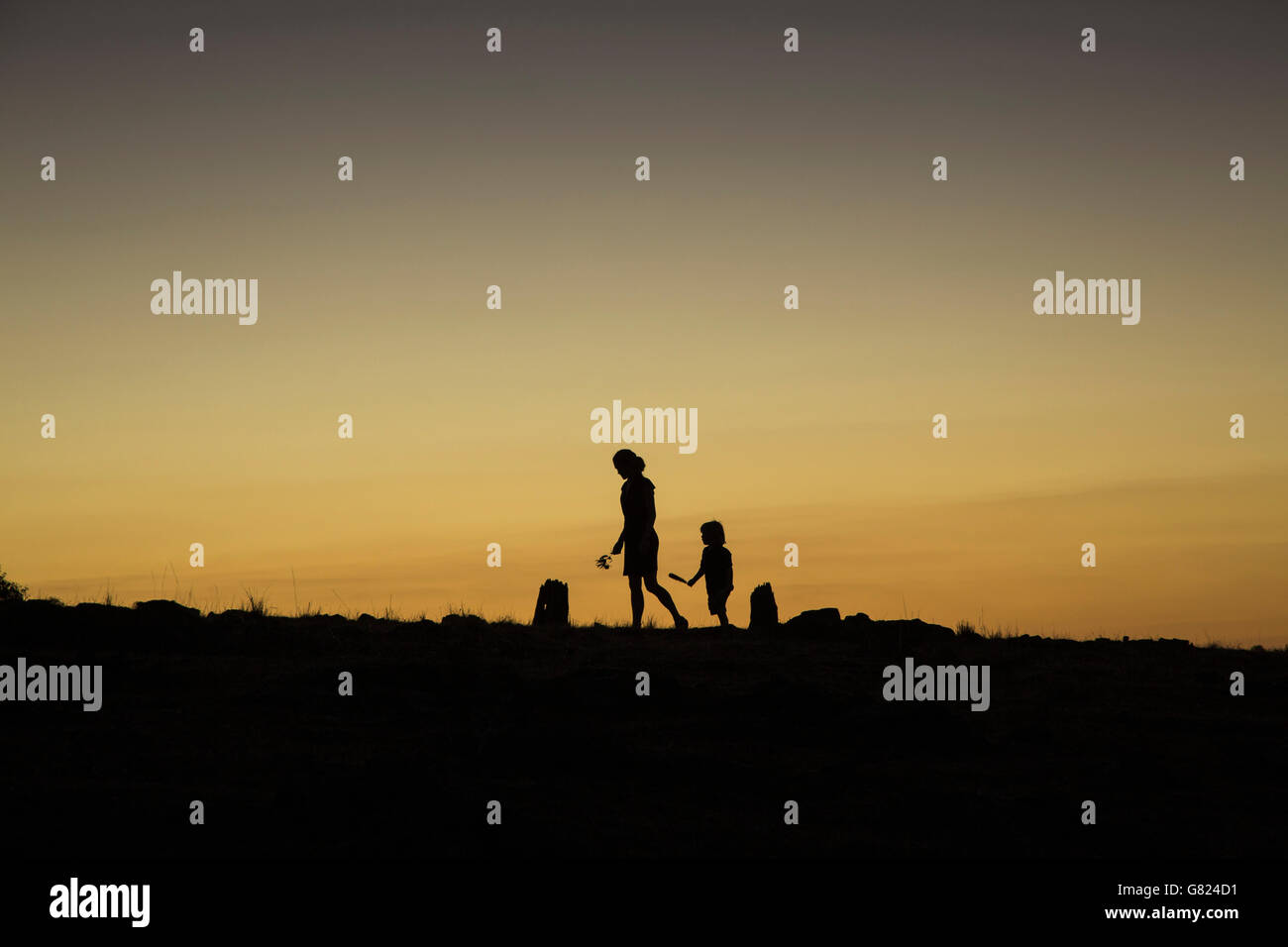 Silhouette Frau und jungen gehen auf auffangene gegen klaren Himmel bei Sonnenuntergang Stockfoto