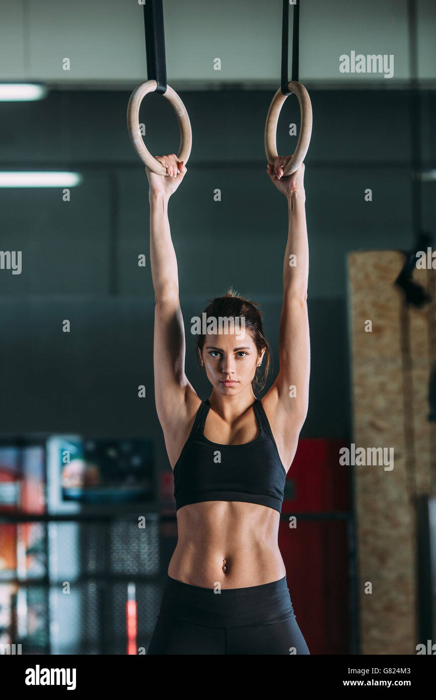 Porträt der jungen Frau hängen von Gymnastik Ringen Stockfoto