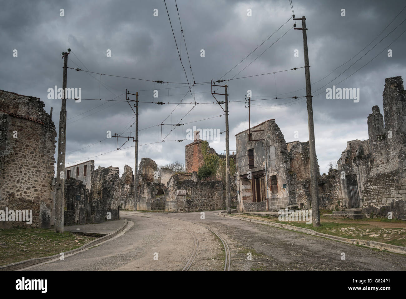 Eisenbahnschienen inmitten von verlassenen Gebäuden in Oradour-Sur-Glane gegen bewölktem Himmel Stockfoto