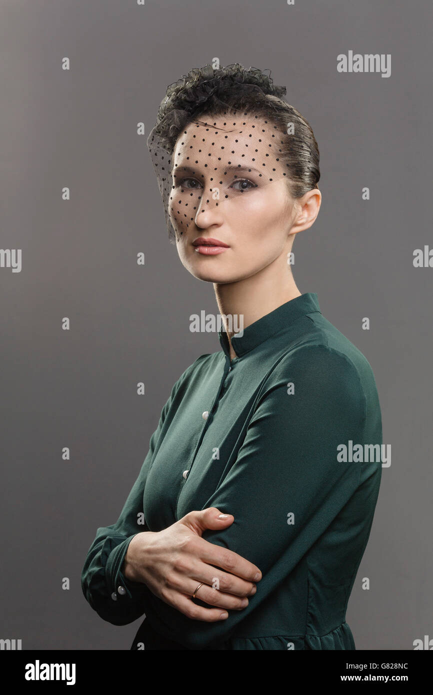 Porträt der selbstbewusste Frau mit Netz für Gesicht vor grauem Hintergrund Stockfoto