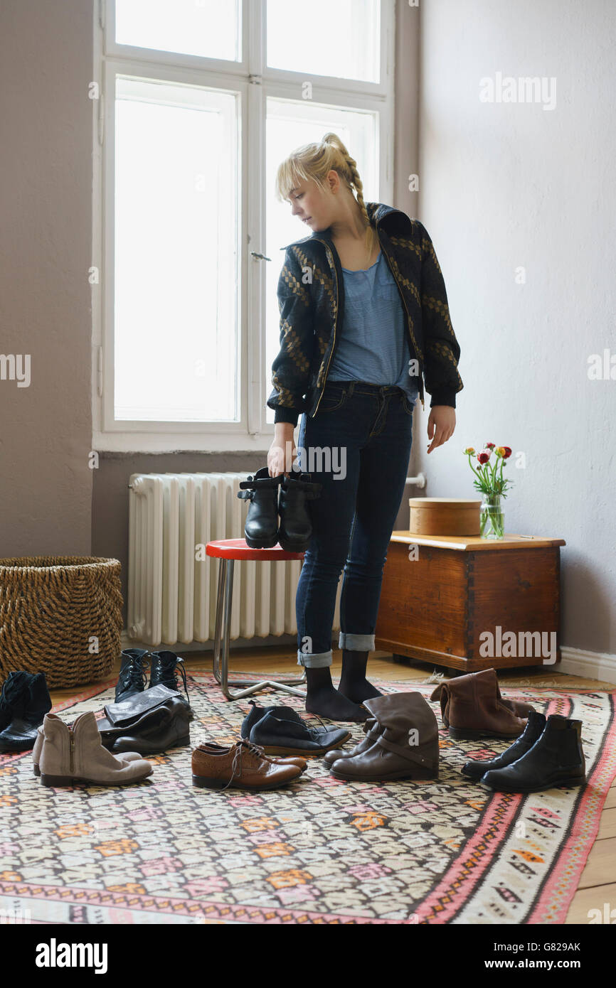 Junge Frau Wahl Schuhe stehen im Wohnzimmer zu Hause Stockfoto