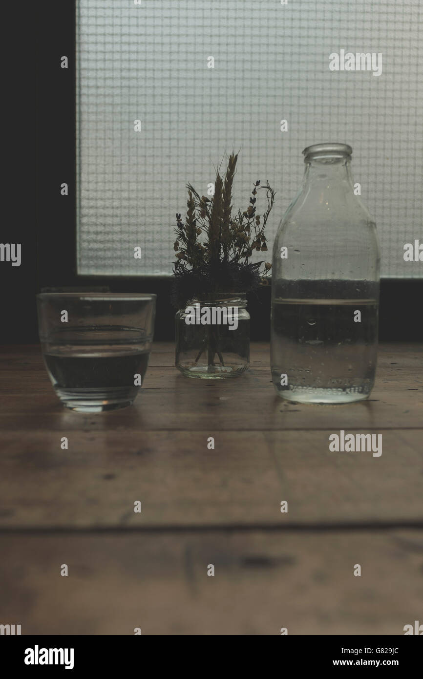 Nahaufnahme von Wasser und Pflanze in Glasbehältern auf Tisch Stockfoto