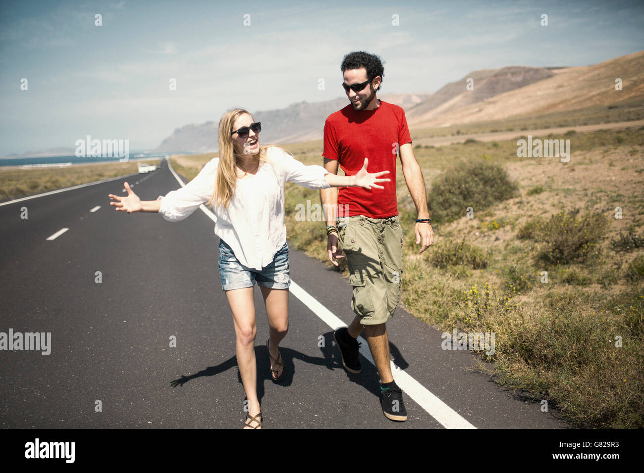 Gesamte Länge der glückliche Frau im Gespräch mit Menschen während des Gehens auf Straße Stockfoto