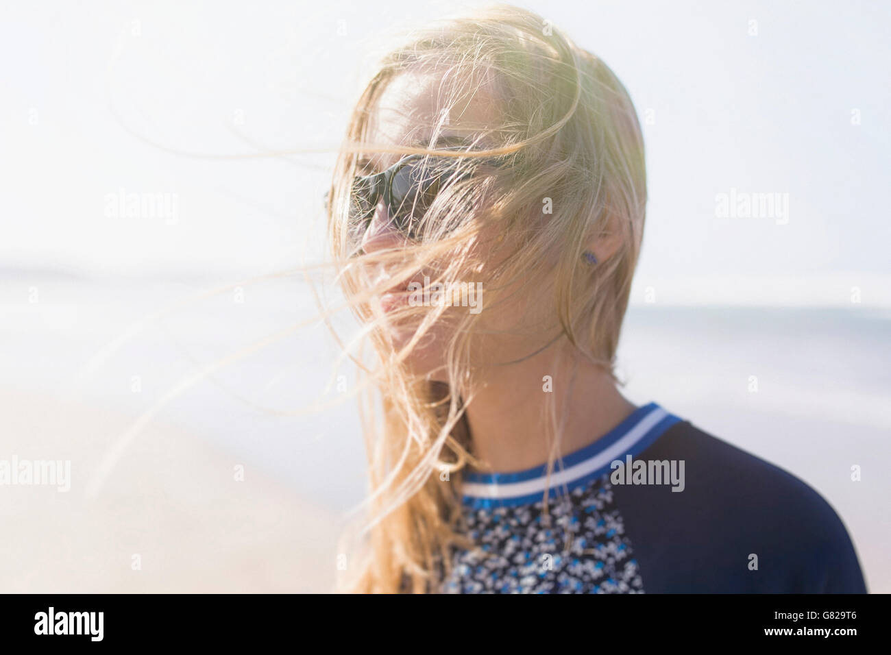 Glückliche junge Frau mit windigen Haar am Strand Stockfoto
