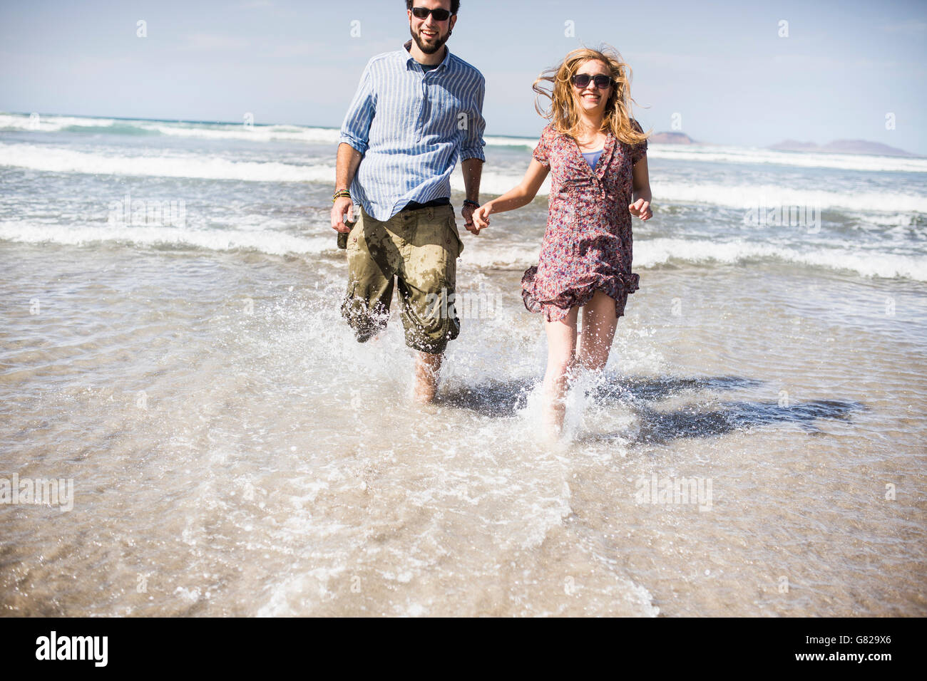 Fröhliches paar im Meer laufen auf sonnigen Tag Stockfoto