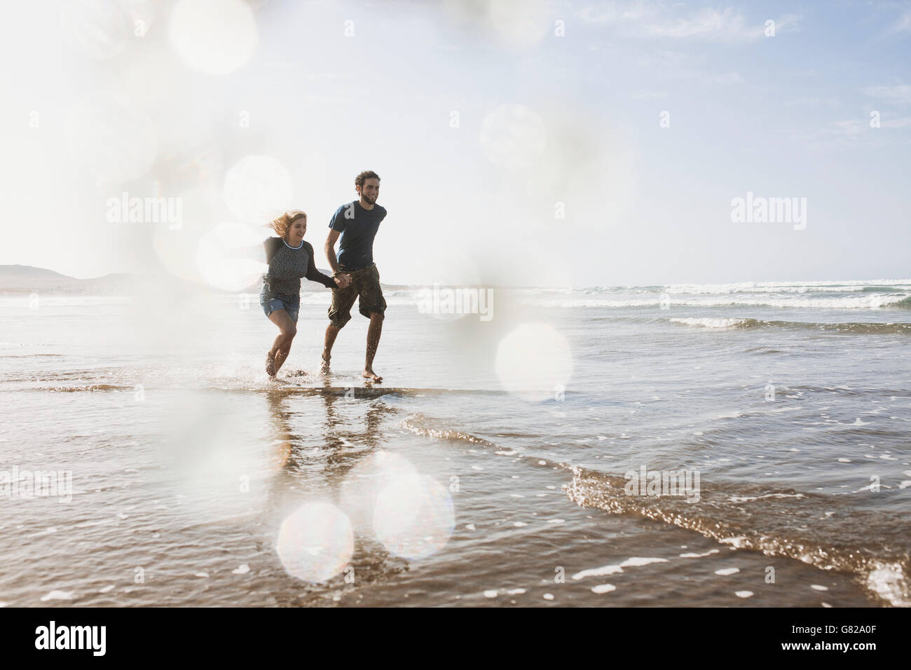 Volle Länge des glücklichen Paares im Meer laufen Stockfoto