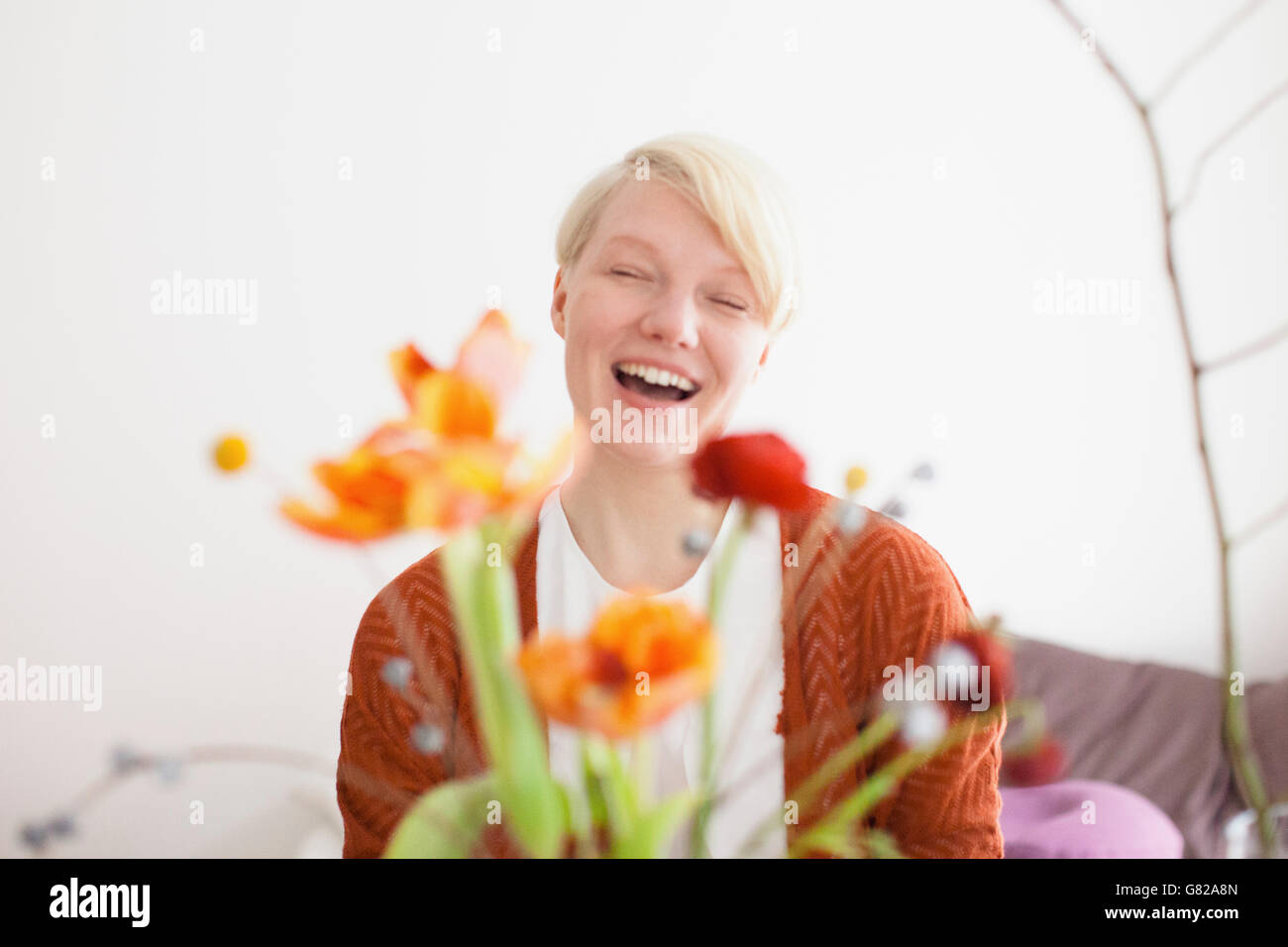 Fröhlich Mitte Erwachsene Frau mit Blumen im Vordergrund zu Hause Stockfoto