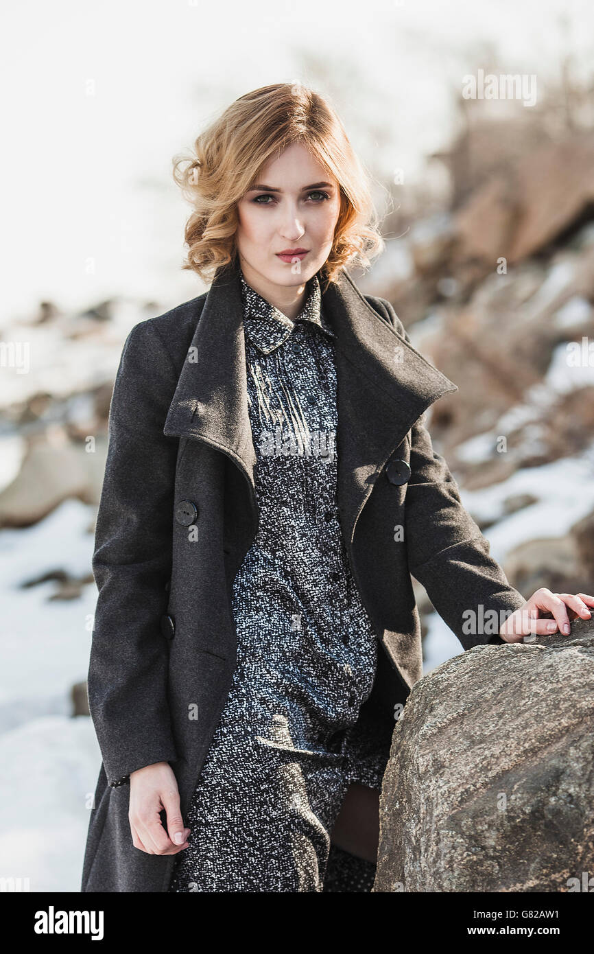 Porträt der schönen jungen Frau trägt lange Mantel stehend von rock Stockfoto