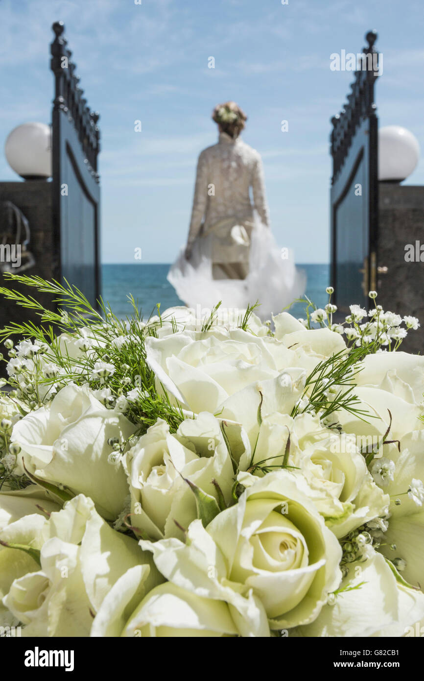 Rückansicht der Braut zu Fuß in Richtung Strand mit Fokus auf rose Bouquet im Vordergrund Stockfoto