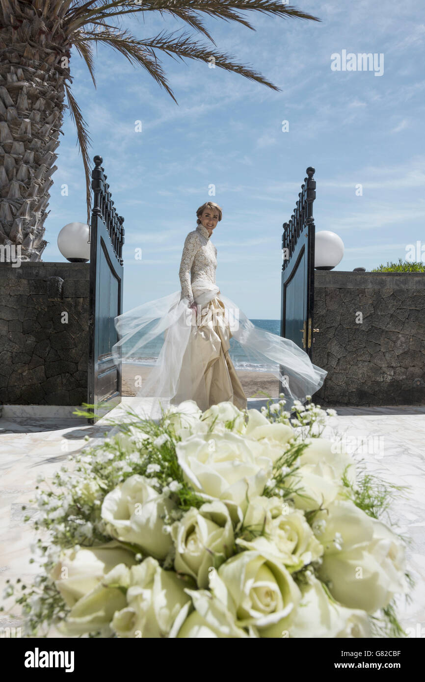 Porträt der glückliche Braut stehen am Eingang mit rose Bouquet im Hintergrund Stockfoto