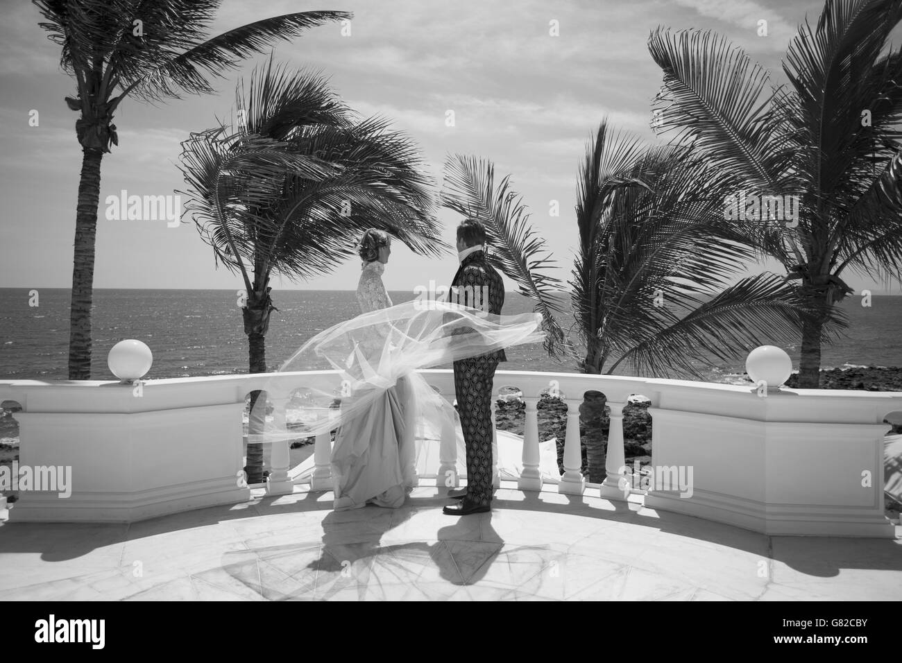Voller Länge von Braut und Bräutigam stehen auf Gebäude Terrasse und Blick auf Meer Stockfoto