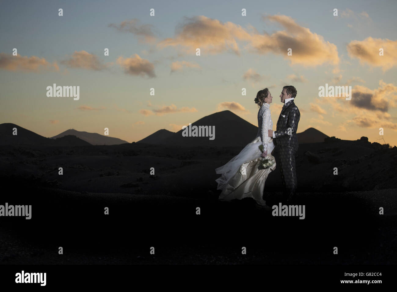 Voller Länge Seitenansicht der romantische Braut und Bräutigam stehen auf vulkanische Landschaft bei Sonnenuntergang Stockfoto