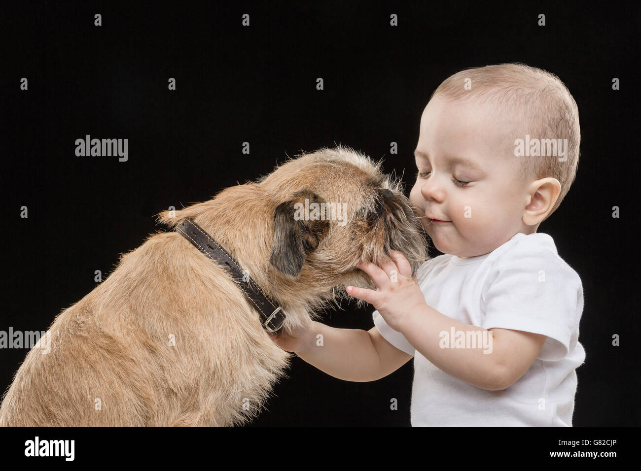 Süsser Boy spielen Hund vor schwarzem Hintergrund Stockfoto