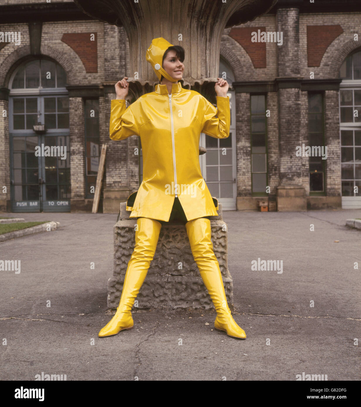 Dianna Lindale trägt ein Outfit, das speziell mit Optilon-Reißverschlüssen entworfen wurde. Jacke in gelber Niolan, Helm und passende Mid-Oberschenkel Stiefel. Gesehen auf der Interleather Exhibition im Alexandra Palace, London. Stockfoto