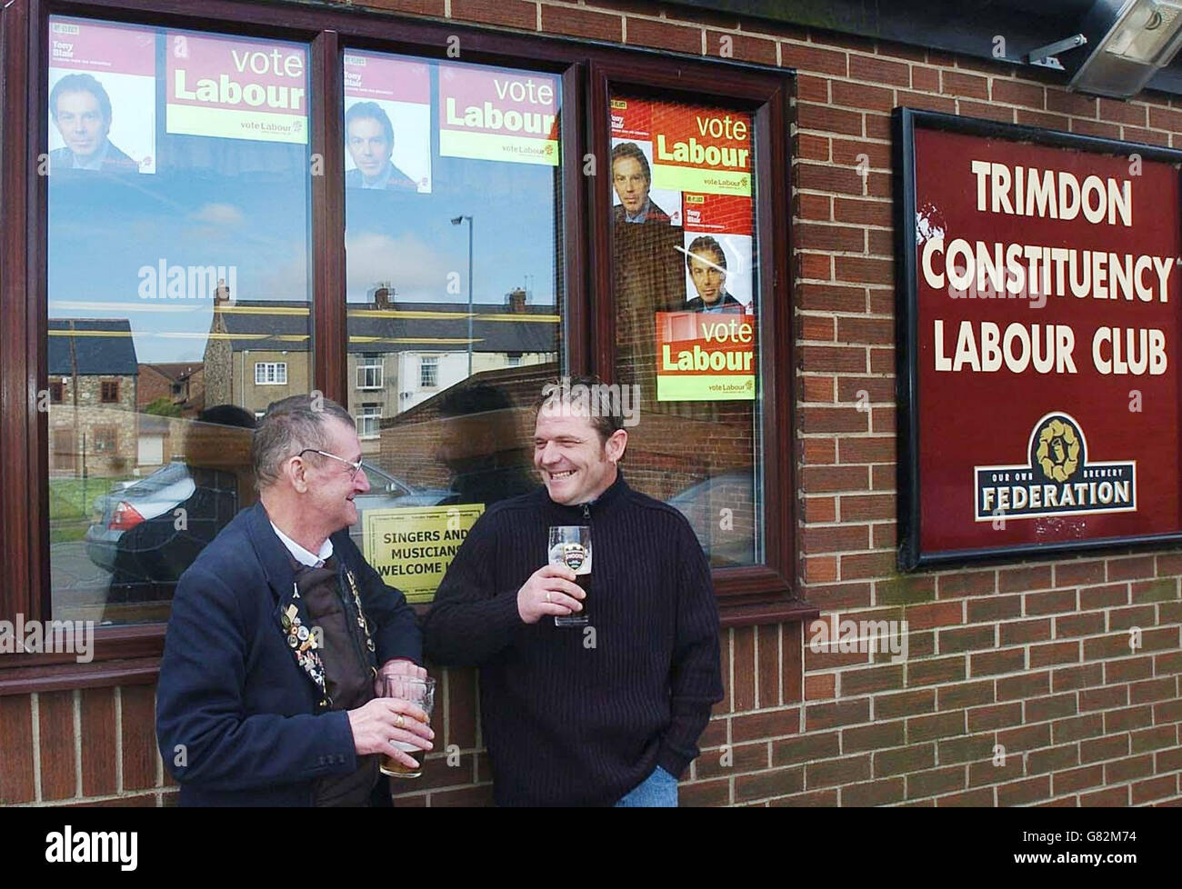 Zwei Gentleman genießen ein Bier unter den Plakaten der Arbeiterkampagne im Trimdon Village Labor Club. Stockfoto