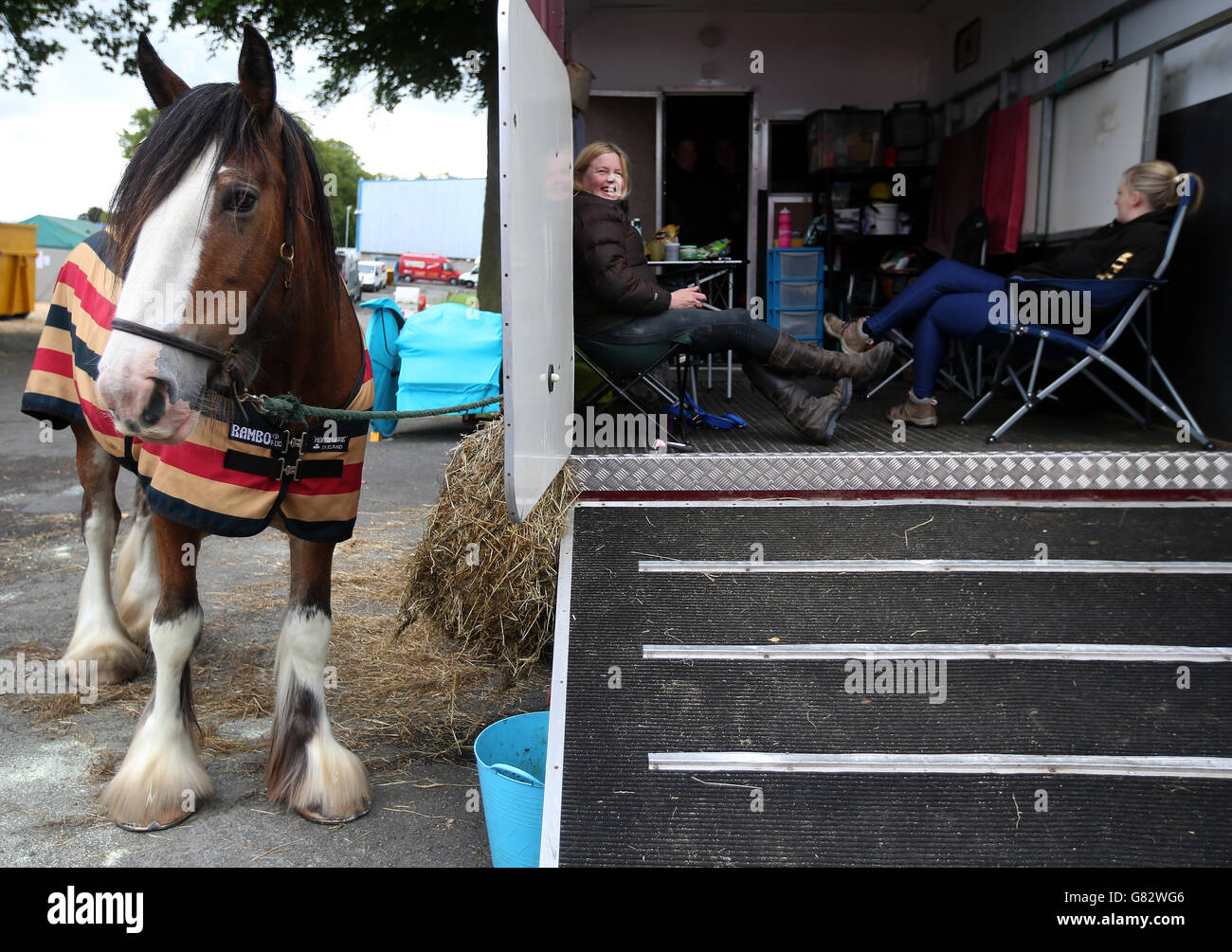 Eine Farmerin macht eine Pause in ihrem Wagen, während ihr Clydesdale Pferd vorbereitet wird, während die Tiere vor der Royal Highland Show in Ingleston, Edinburgh ankommen. Stockfoto