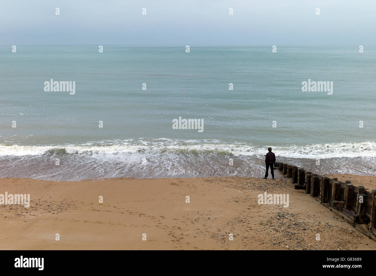 einsamer Mann stehend am Meeresstrand. Brighton, UK Stockfoto