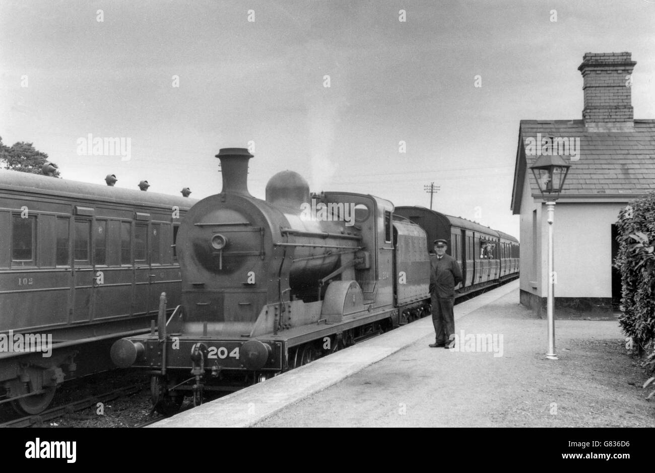 Irische Eisenbahnen Klasse J12 4-4-0 Antrim mit einem Zug an einem unbekannten Station in Irland. C1953. Stockfoto