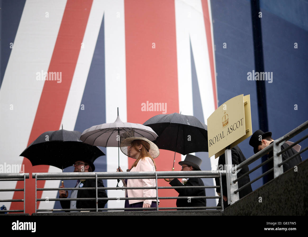 Rennfahrer, die am fünften Tag des Royal Ascot Meeting 2015 auf der Ascot Racecourse, Berkshire, Regenschirme halten. Stockfoto