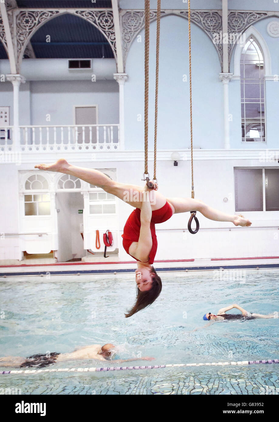 Danuta Ramos vom All or Nothing Aerial Dance Theatre tritt auf einem Trapez über einem Swimmingpool im Western Baths Club in Glasgow auf, bevor das Unternehmen seine neue Tourenshow Three's A Crowd vorstellt. Stockfoto