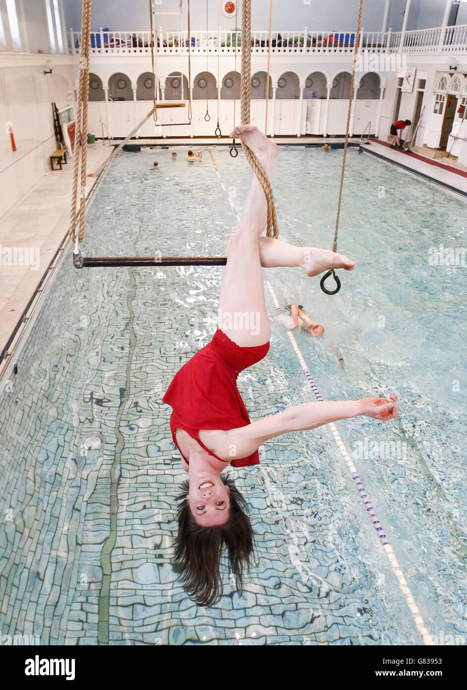 Danuta Ramos vom All or Nothing Aerial Dance Theatre tritt auf einem Trapez über einem Swimmingpool im Western Baths Club in Glasgow auf, bevor das Unternehmen seine neue Tourenshow Three's A Crowd vorstellt. Stockfoto