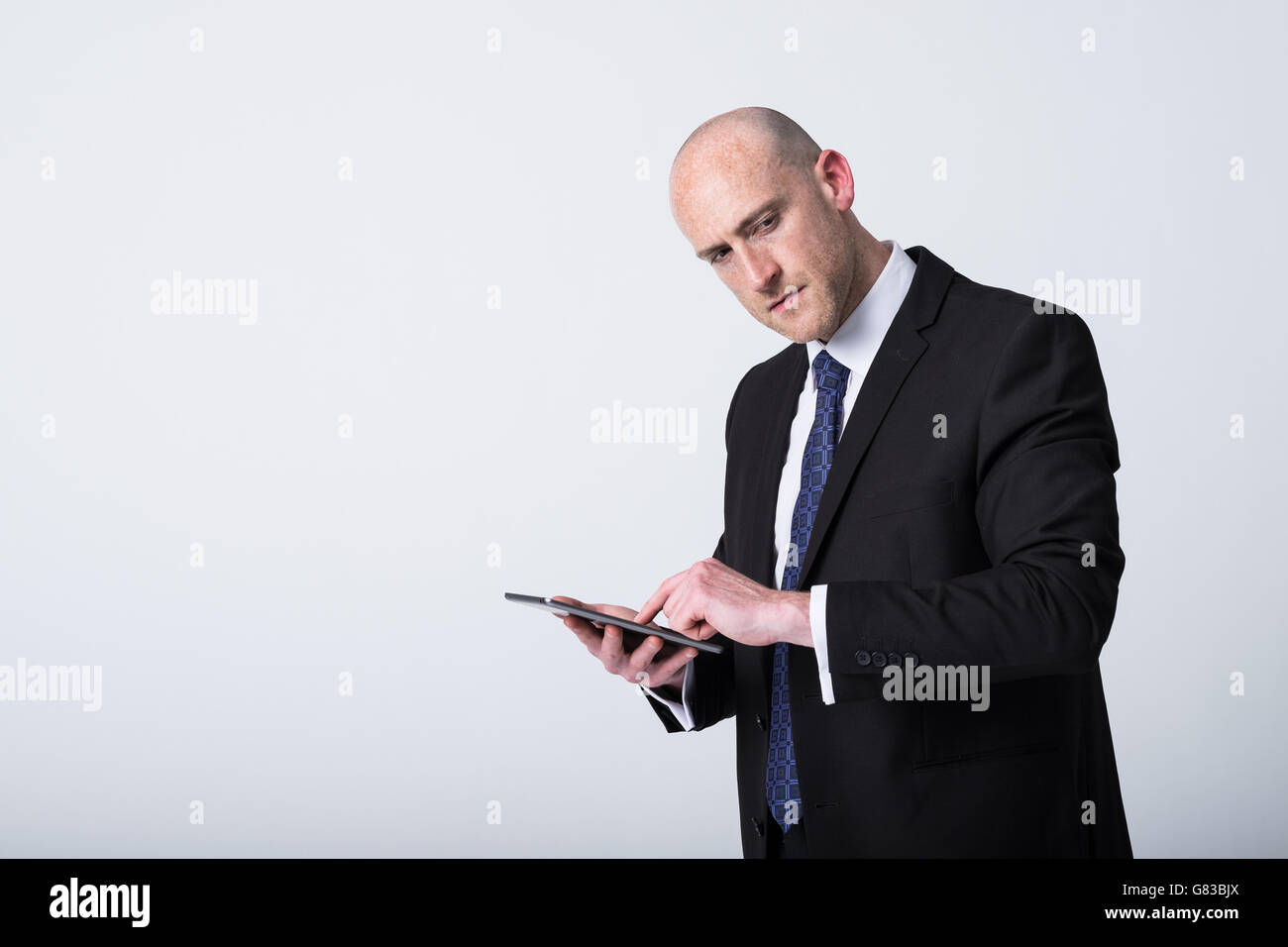 Glatzenkaufmann, der ein elektronisches Tablet hält und nutzt, um Arbeitsprobleme zu lösen. Kopieren Sie den Platz links vom Bild Stockfoto