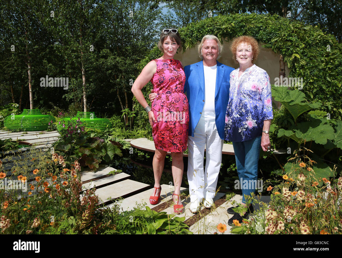 Die Botschafter von Macmillan, David Emanuel und Judy Parfitt, besuchen den Macmillan Cancer Support Legacy Garden mit der Erschaffer des Gartens, der preisgekrönten Gartendesignerin Ann-Marie Powell (links), bei der Hampton Court Flower Show im Hampton Court Palace in Surrey. Stockfoto